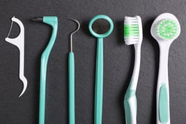 Selection of dentist brushes and tools on a black slate surface-1